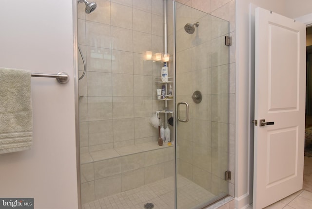 bathroom with a shower with door and tile patterned floors