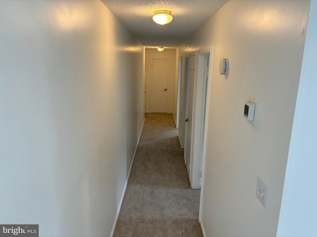 corridor with light colored carpet and a textured ceiling