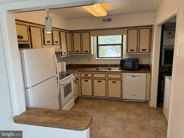 kitchen featuring white appliances, a textured ceiling, and sink