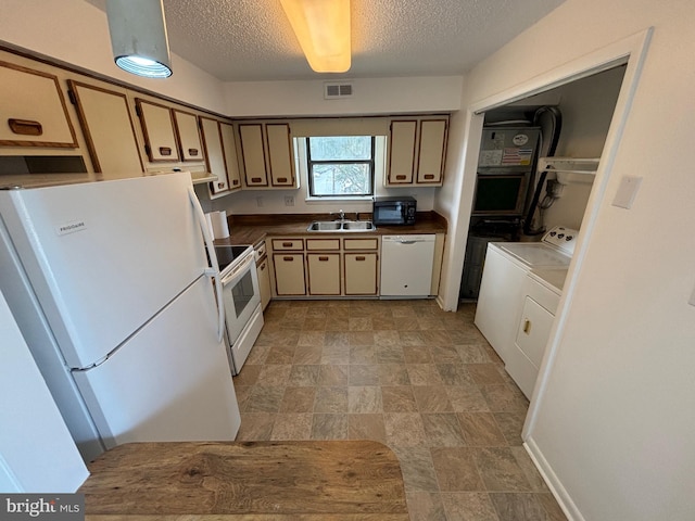 kitchen featuring a textured ceiling, separate washer and dryer, white appliances, and sink