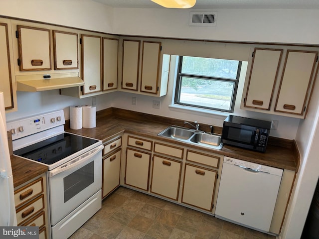 kitchen with white appliances, cream cabinets, and sink