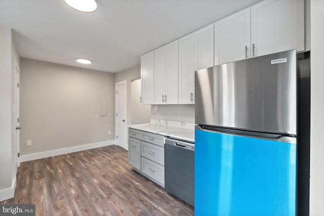 kitchen featuring white cabinetry, dark hardwood / wood-style floors, stainless steel appliances, and light stone counters