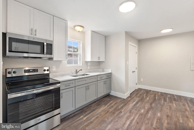 kitchen featuring appliances with stainless steel finishes, gray cabinetry, dark wood-type flooring, white cabinets, and sink