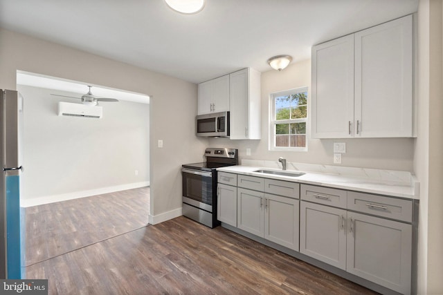 kitchen with sink, a wall mounted air conditioner, stainless steel appliances, dark hardwood / wood-style flooring, and ceiling fan