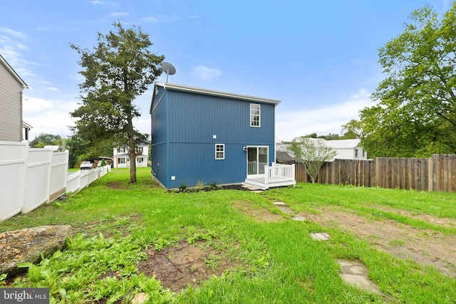 back of property with a lawn and a wooden deck