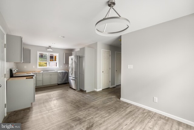 kitchen with gray cabinets, stainless steel fridge, and light hardwood / wood-style floors