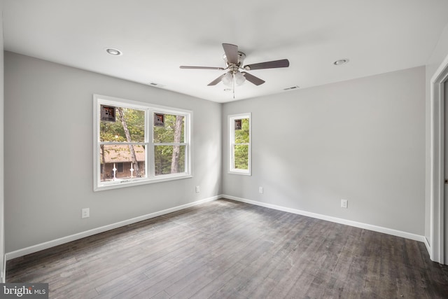 empty room featuring ceiling fan, plenty of natural light, and dark wood-type flooring