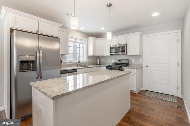 kitchen featuring hanging light fixtures, a kitchen island, white cabinetry, stainless steel appliances, and dark hardwood / wood-style flooring