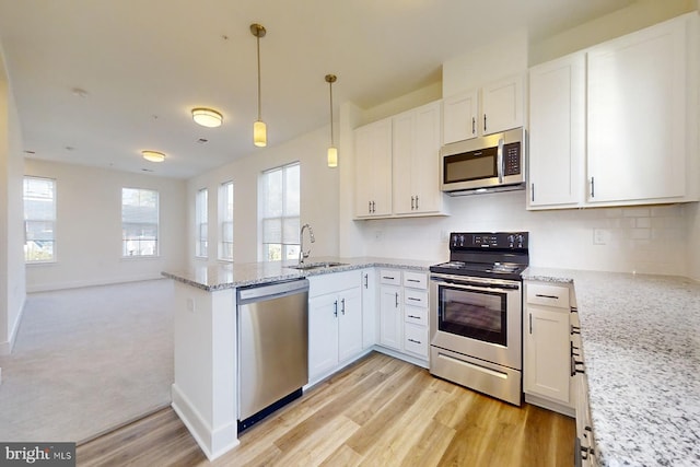 kitchen featuring hanging light fixtures, kitchen peninsula, stainless steel appliances, and white cabinets