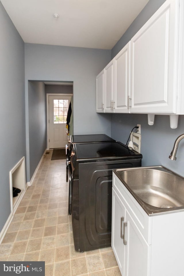 laundry room with sink, washing machine and clothes dryer, and cabinets