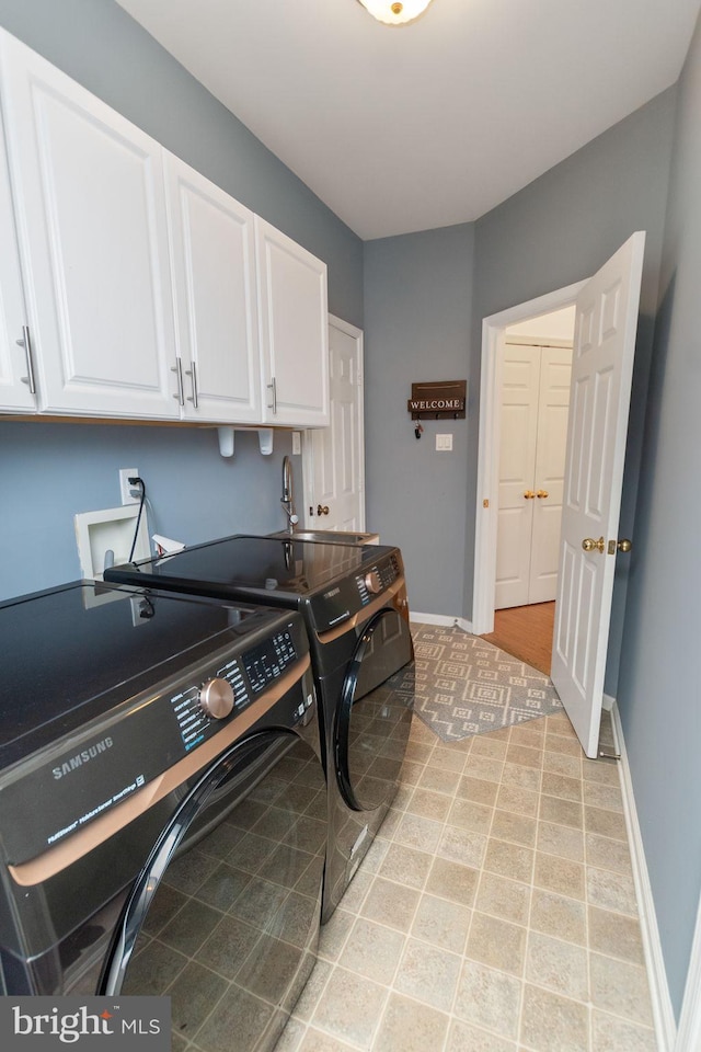 clothes washing area with separate washer and dryer and cabinets