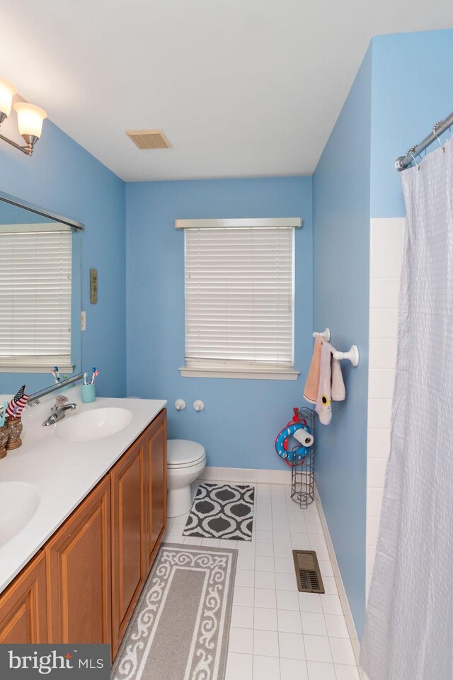 bathroom featuring vanity, tile patterned flooring, toilet, and curtained shower