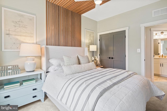 bedroom featuring visible vents, ensuite bathroom, light carpet, and ceiling fan