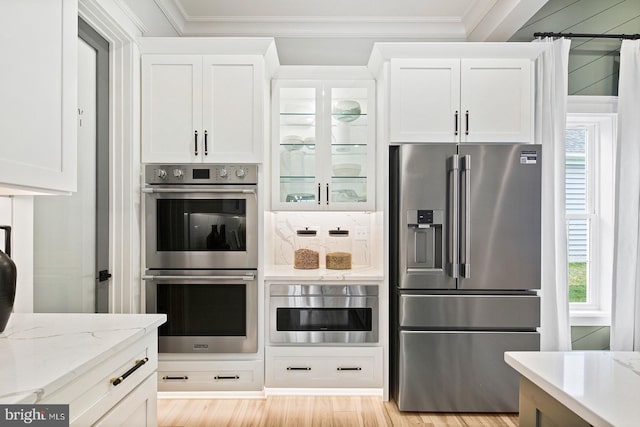 kitchen with appliances with stainless steel finishes, white cabinets, and a healthy amount of sunlight