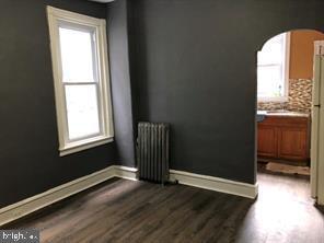 spare room with plenty of natural light, dark hardwood / wood-style flooring, and radiator heating unit