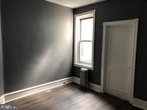 unfurnished room with radiator and hardwood / wood-style floors