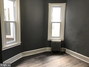 empty room with wood-type flooring and radiator heating unit