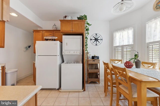 kitchen featuring stacked washer and dryer, white fridge, and light tile patterned floors