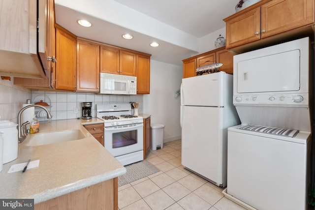 kitchen with white appliances, tasteful backsplash, sink, stacked washer / drying machine, and light tile patterned floors