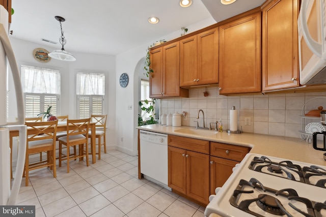 kitchen with white appliances, tasteful backsplash, sink, hanging light fixtures, and light tile patterned floors