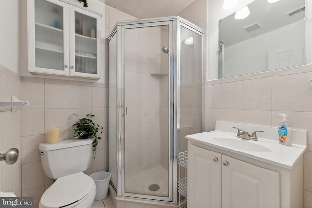 bathroom featuring toilet, an enclosed shower, vanity, and tile walls