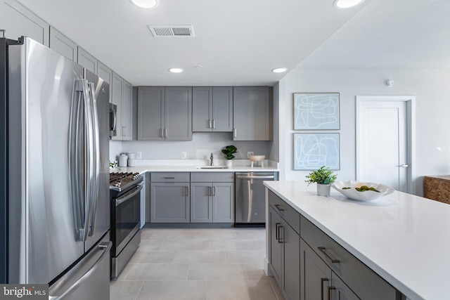 kitchen featuring gray cabinets, stainless steel appliances, light tile patterned floors, and sink