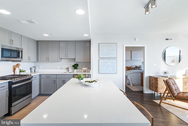 kitchen featuring stainless steel appliances, dark hardwood / wood-style floors, sink, and gray cabinetry