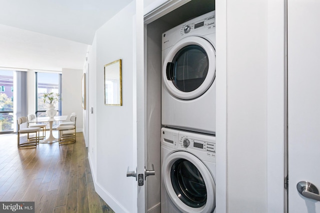 clothes washing area with dark hardwood / wood-style floors and stacked washing maching and dryer