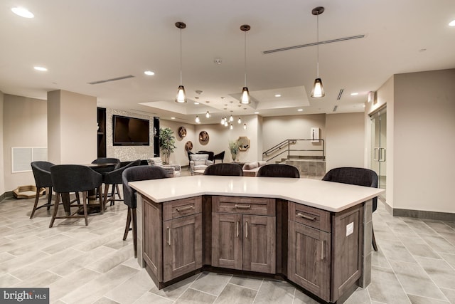 kitchen featuring a raised ceiling, a kitchen bar, a center island, and decorative light fixtures