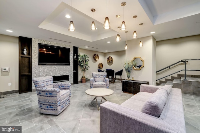 living room featuring a raised ceiling and a large fireplace