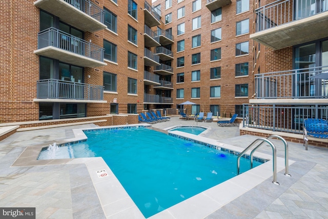 view of swimming pool with a hot tub and a patio area