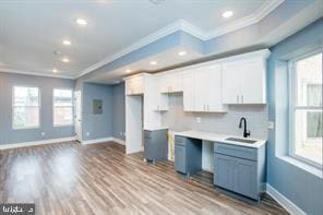 kitchen featuring light wood-type flooring, sink, white cabinets, backsplash, and ornamental molding