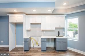 kitchen with white cabinets, backsplash, dark hardwood / wood-style flooring, crown molding, and sink