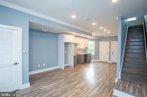 unfurnished living room featuring hardwood / wood-style flooring and crown molding