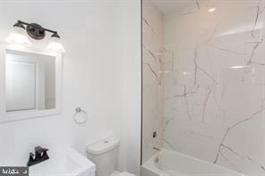 full bathroom featuring sink, tiled shower / bath combo, and toilet