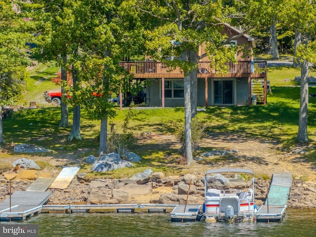 rear view of property featuring a deck with water view and a yard