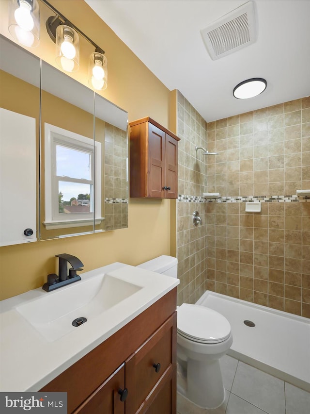 bathroom featuring vanity, tile patterned floors, toilet, and tiled shower