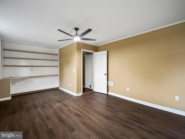 unfurnished room featuring ceiling fan, dark hardwood / wood-style floors, built in desk, and crown molding