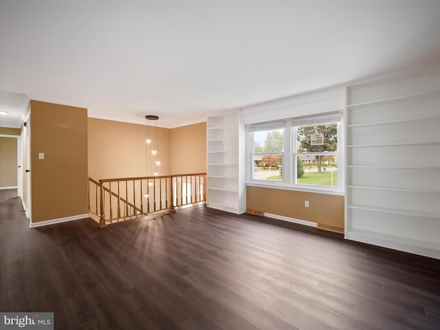 empty room with ornamental molding, dark hardwood / wood-style flooring, and built in features