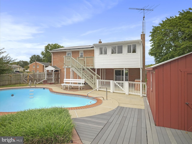 view of swimming pool with a shed, a wooden deck, and a patio area