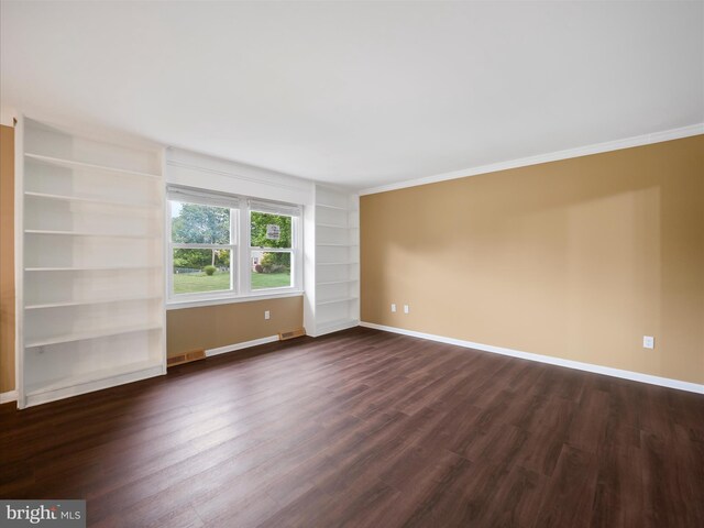 unfurnished room with built in shelves, ornamental molding, and dark hardwood / wood-style floors