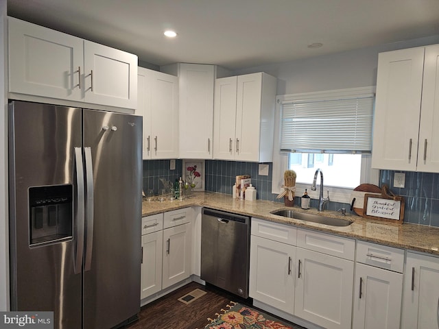 kitchen featuring decorative backsplash, white cabinets, appliances with stainless steel finishes, and sink