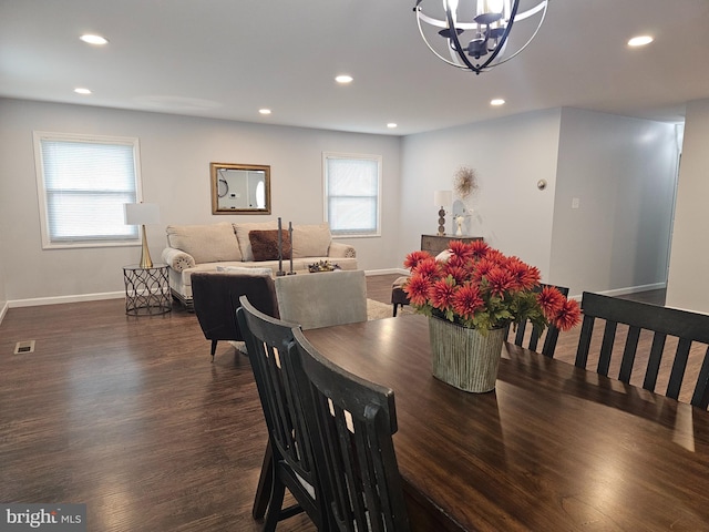 dining space featuring a healthy amount of sunlight, dark wood-type flooring, and a chandelier