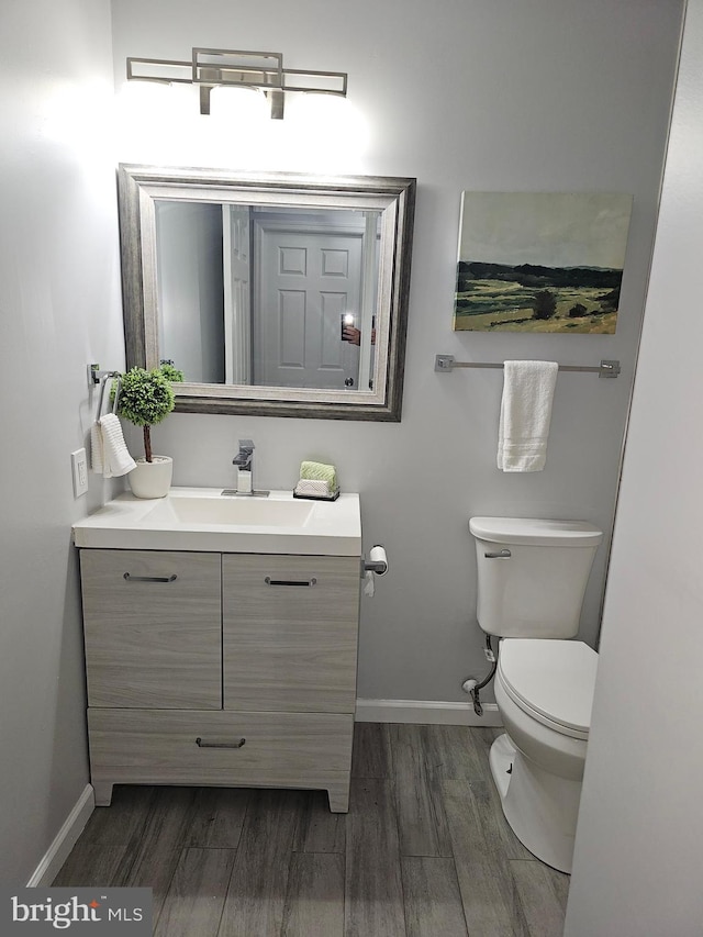 bathroom with wood-type flooring, vanity, and toilet