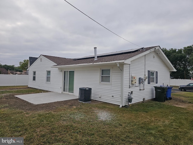 rear view of house with central AC unit, a lawn, and a patio