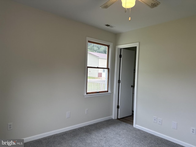 unfurnished room with dark colored carpet and ceiling fan