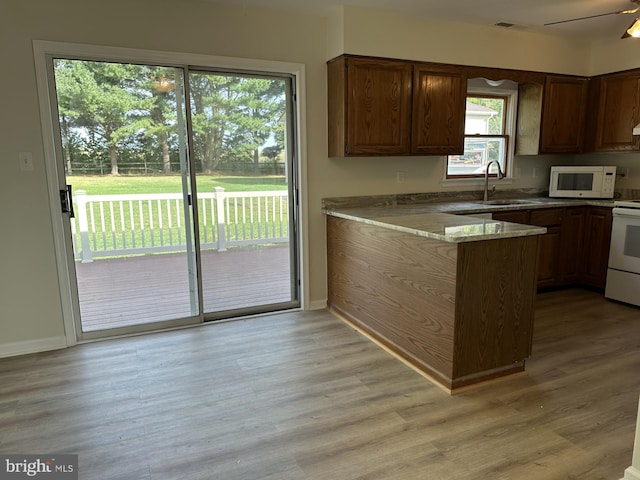 kitchen with kitchen peninsula, white appliances, light hardwood / wood-style floors, and ceiling fan