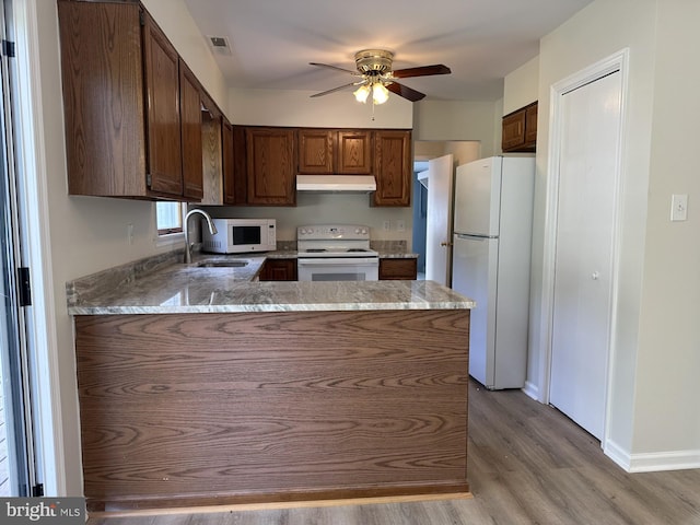 kitchen featuring wood-type flooring, sink, kitchen peninsula, white appliances, and ceiling fan