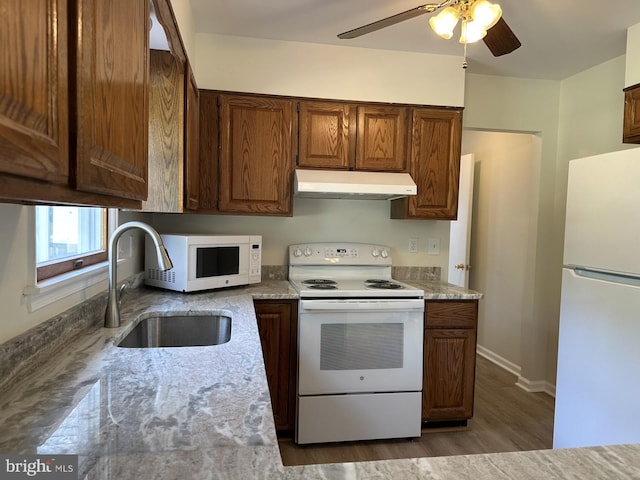 kitchen with ceiling fan, sink, white appliances, wood-type flooring, and light stone countertops