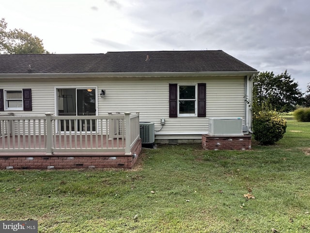 rear view of property featuring a yard, a wooden deck, and central AC